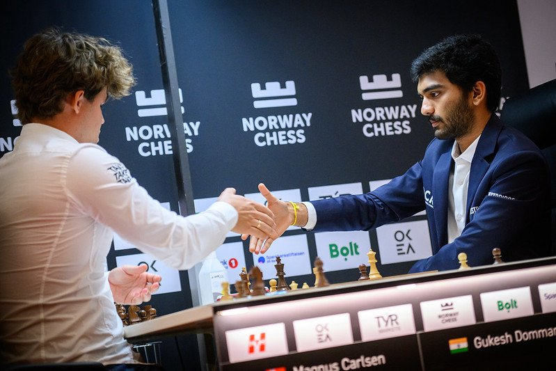 Magnus Carlsen and Gukesh D face off across the chessboard at Norway Chess 2025, intensely focused during a pivotal moment in their match, with spectators watching in suspense.